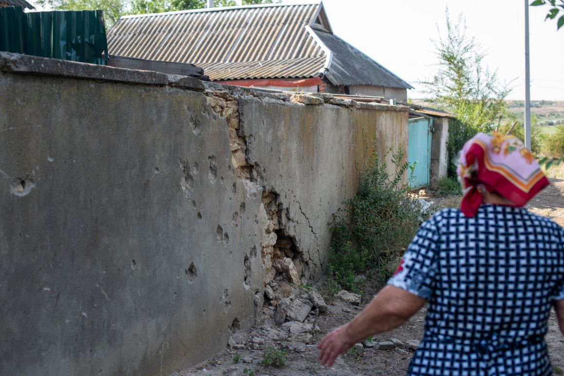 Lidia Fedorivna Aleksandrova (geb. 1937) vor einer Wand im Dorf mit Einschusslöchern in einem Dorf im Gebiet Mykolajiw 